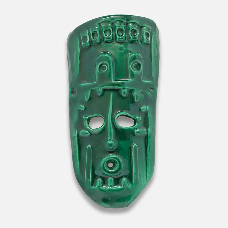 Figurative ceramic mask sculpture by Giorgio Crisafi, green glaze, shield-shaped with geometric apertures and battlement crown, Masks series. Title: Maschera Zufolo II