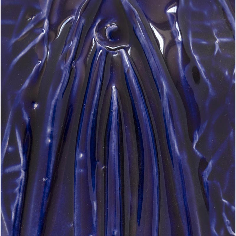 View in a room of a figurative ceramic mask sculpture by Giorgio Crisafi, deep ultramarine blue glaze with vertical draped texture, Masks series. Title: Maschera Blu II