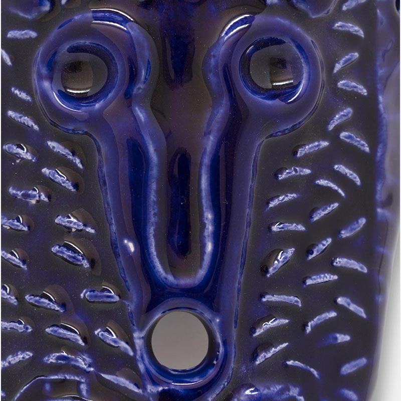Detail of a figurative ceramic mask sculpture by Giorgio Crisafi, cobalt blue glaze on all-over diagonal incised surface, pointed almond form, Masks series. Title: Maschera Blu I